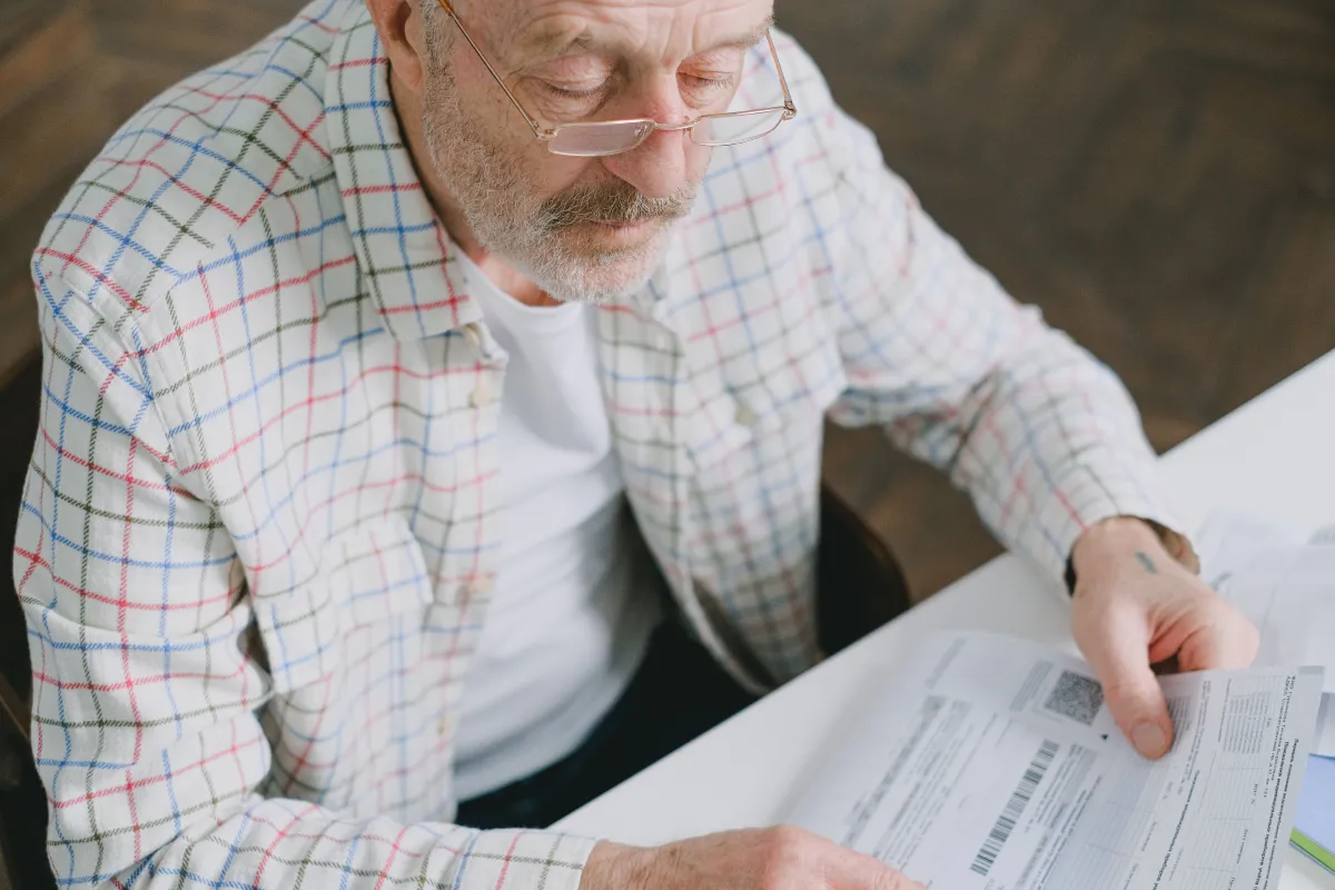 Will you pay more for Medicare? Understanding income‑based premiums - Elderly man in glasses carefully examines documents