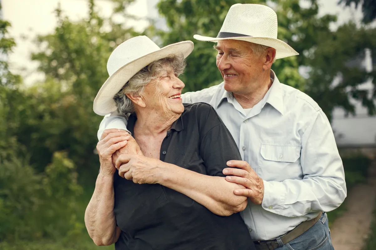 Planning for what’s next: is a CCRC right for you? - Happy senior couple wearing hats, sharing a joyful moment outdoors.